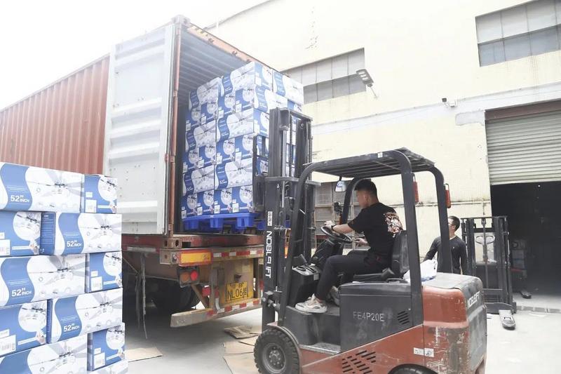 Person operating a forklift unloading stacked boxes from a truck.