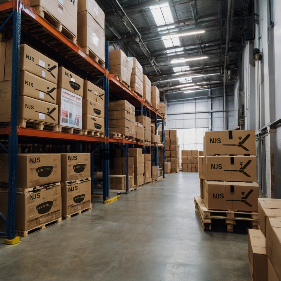Warehouse with stacked cardboard boxes of fans and lights labelled 'NJS' on shelves and pallets.